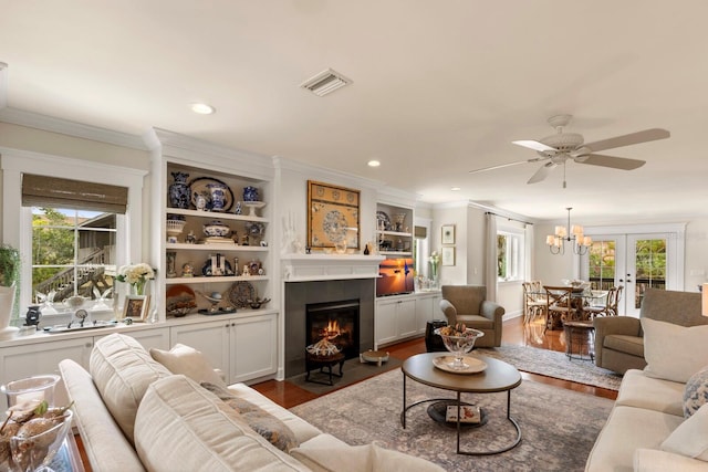 living room featuring visible vents, dark wood finished floors, a fireplace with flush hearth, recessed lighting, and crown molding