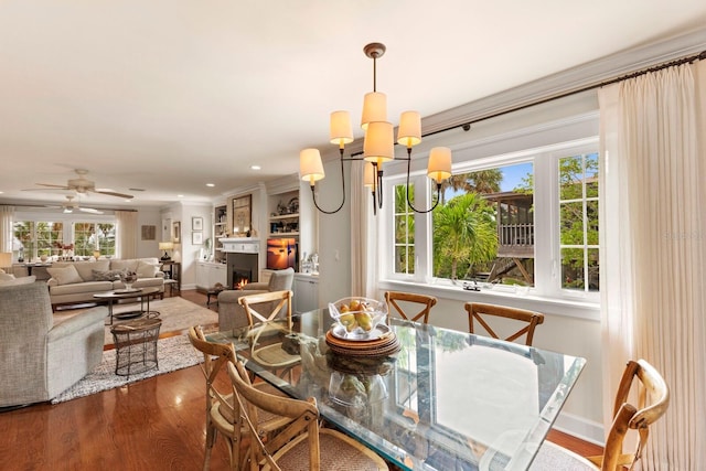 dining room featuring ornamental molding, dark wood-style floors, recessed lighting, a lit fireplace, and baseboards