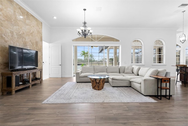 living room with a chandelier, visible vents, ornamental molding, and wood finished floors