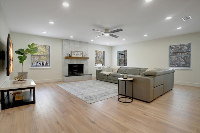 living area with a high end fireplace, visible vents, recessed lighting, and light wood-type flooring