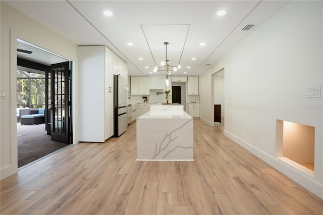 kitchen with visible vents, decorative backsplash, light wood-style floors, high end fridge, and white cabinetry