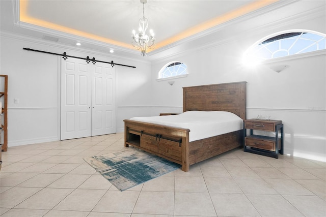 bedroom with light tile patterned floors, a tray ceiling, a barn door, and ornamental molding