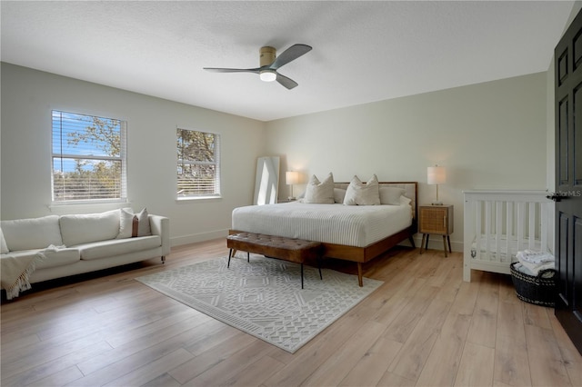 bedroom featuring light wood finished floors, ceiling fan, a textured ceiling, and baseboards