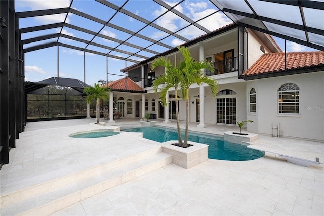 outdoor pool with glass enclosure, a patio, and an in ground hot tub