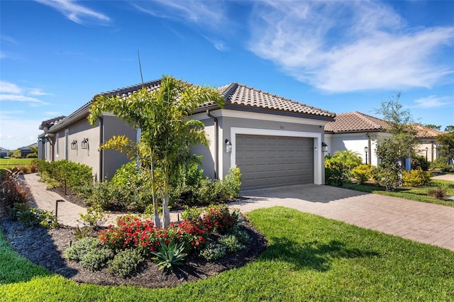 view of front facade with a front yard, stucco siding, a garage, a tiled roof, and decorative driveway