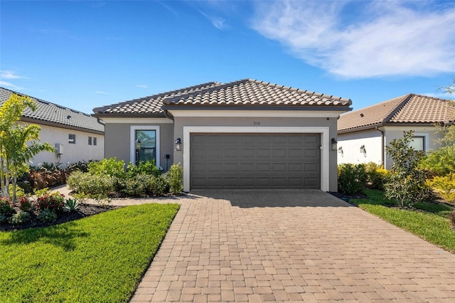 mediterranean / spanish-style house featuring stucco siding, a tile roof, decorative driveway, and a garage