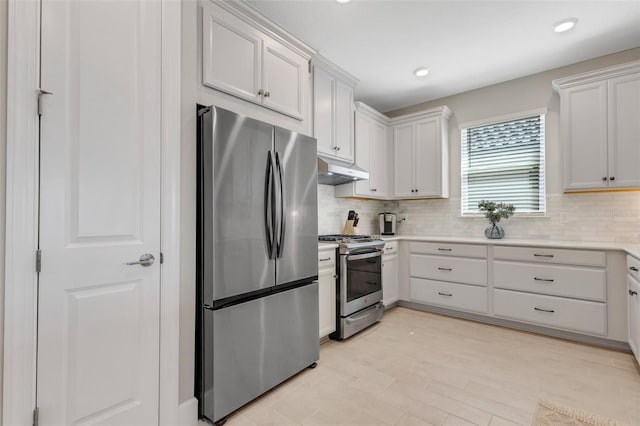 kitchen featuring under cabinet range hood, backsplash, light countertops, and appliances with stainless steel finishes