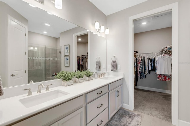 full bathroom with a shower stall, double vanity, baseboards, and a sink