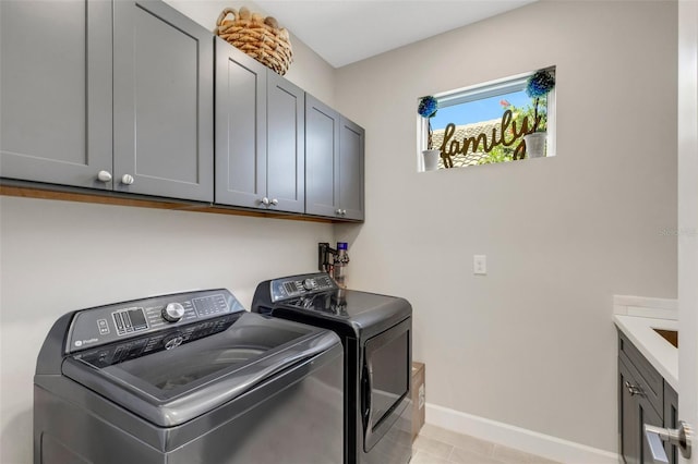 clothes washing area with washing machine and clothes dryer, cabinet space, and baseboards