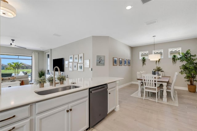 kitchen with a sink, light countertops, white cabinets, dishwasher, and light wood-type flooring