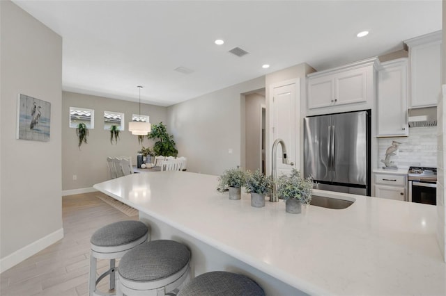 kitchen with a kitchen bar, visible vents, white cabinetry, and stainless steel appliances