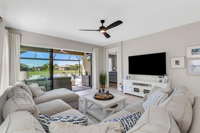 living area featuring visible vents, light wood-style flooring, a ceiling fan, and a sunroom