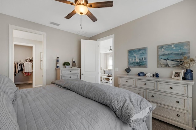 bedroom with visible vents, a ceiling fan, carpet, baseboards, and a spacious closet