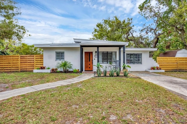 view of front of house featuring stucco siding, a front yard, and fence