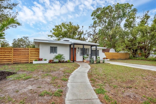 mid-century home featuring a front lawn, fence, and stucco siding