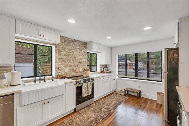 kitchen with a sink, decorative backsplash, wood finished floors, and stainless steel appliances