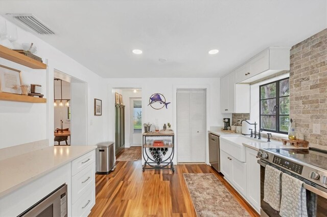 kitchen with visible vents, light wood finished floors, stainless steel appliances, white cabinets, and light countertops