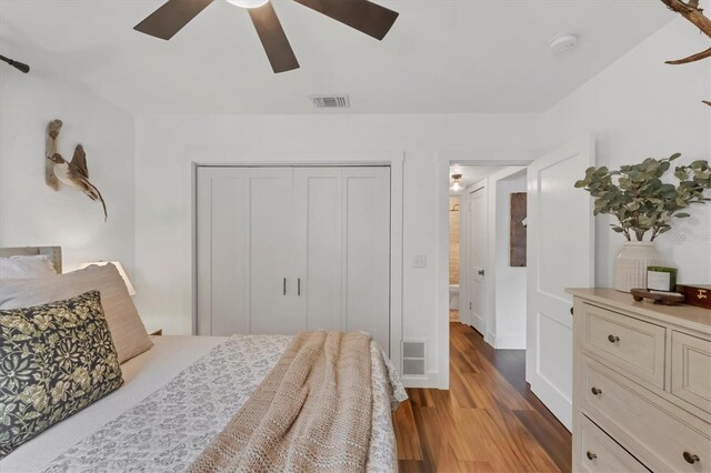 bedroom featuring visible vents, a closet, wood finished floors, and a ceiling fan