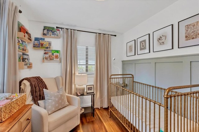 bedroom featuring a nursery area and wood finished floors