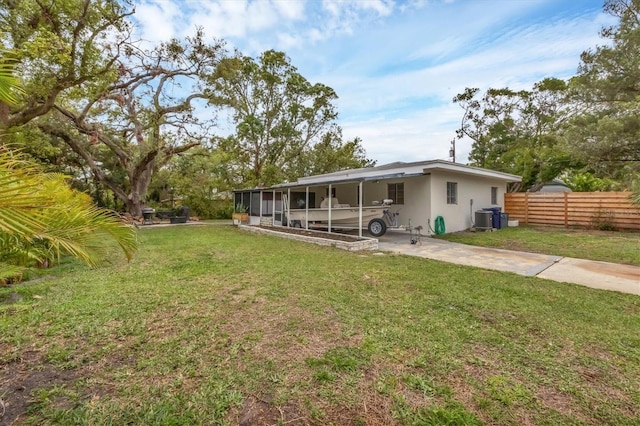 exterior space with fence, driveway, central AC, a sunroom, and a lawn