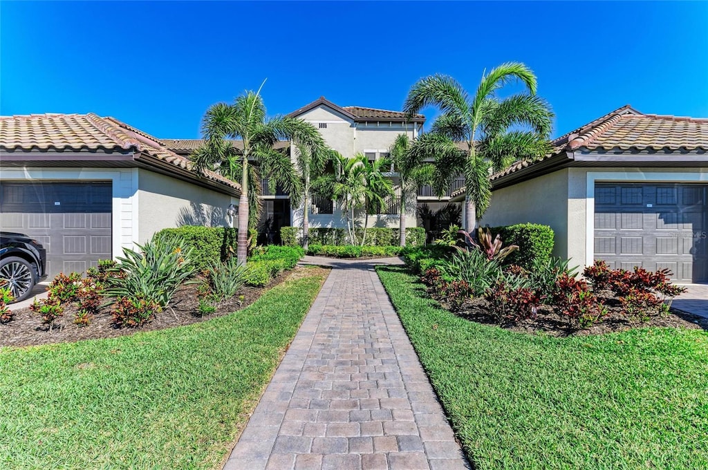 mediterranean / spanish-style home with a tile roof, a garage, and stucco siding