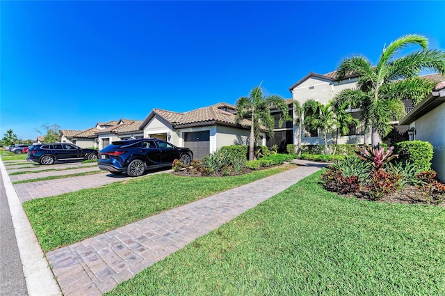 view of front facade with a front lawn, a tiled roof, stucco siding, driveway, and an attached garage