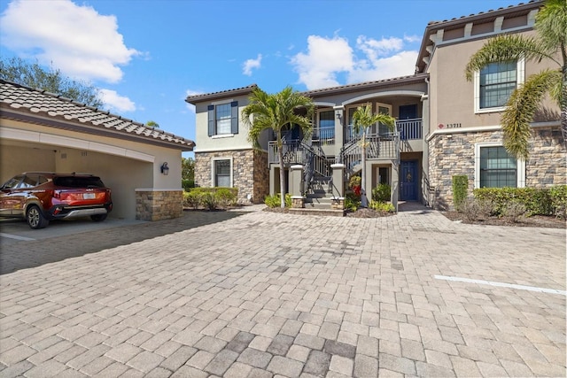 mediterranean / spanish-style home with stucco siding, stone siding, driveway, and stairway