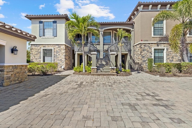 view of front of house featuring stairway, stone siding, and stucco siding