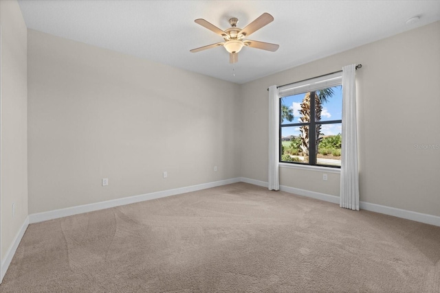 spare room featuring baseboards, light colored carpet, and ceiling fan