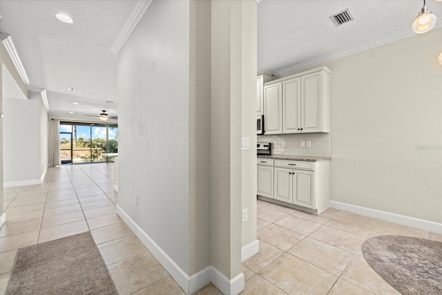 hallway with light tile patterned flooring, baseboards, visible vents, and ornamental molding