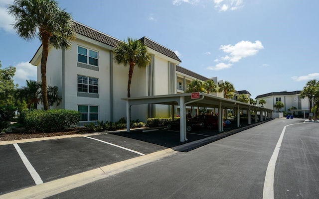 view of property featuring covered and uncovered parking