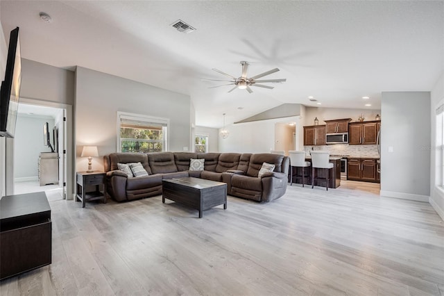 living room featuring visible vents, light wood-style flooring, baseboards, lofted ceiling, and ceiling fan