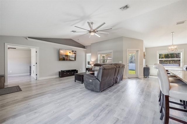 living room featuring visible vents, lofted ceiling, light wood-style flooring, and ceiling fan with notable chandelier