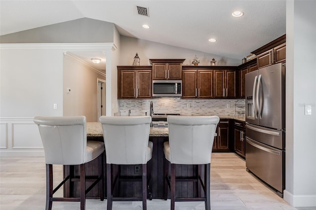 kitchen with dark brown cabinets, appliances with stainless steel finishes, and lofted ceiling