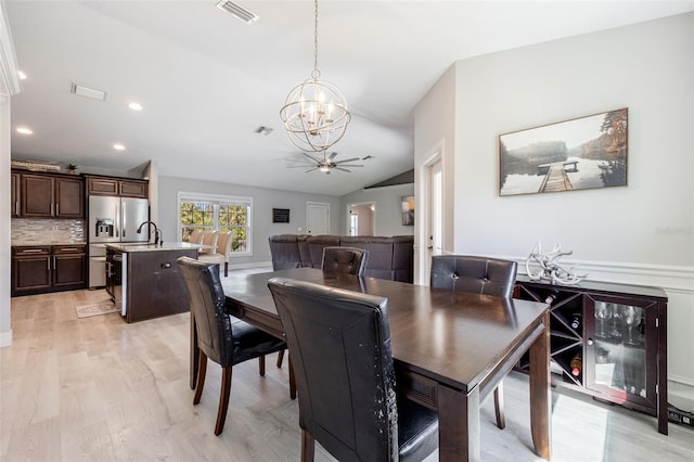 dining space featuring lofted ceiling, ceiling fan with notable chandelier, visible vents, and light wood finished floors