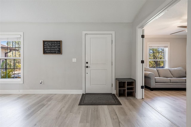 foyer featuring ceiling fan, baseboards, and light wood-style floors