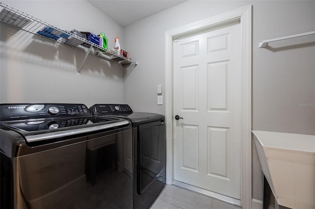 washroom with laundry area, washing machine and dryer, and light wood-style flooring