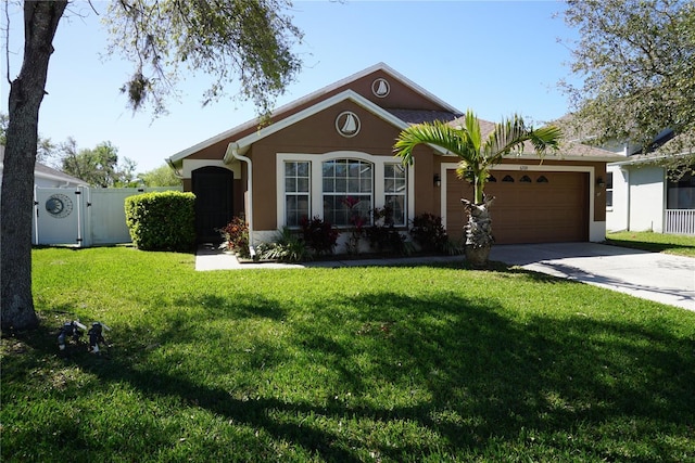 view of front facade with a front lawn, stucco siding, a garage, driveway, and a gate