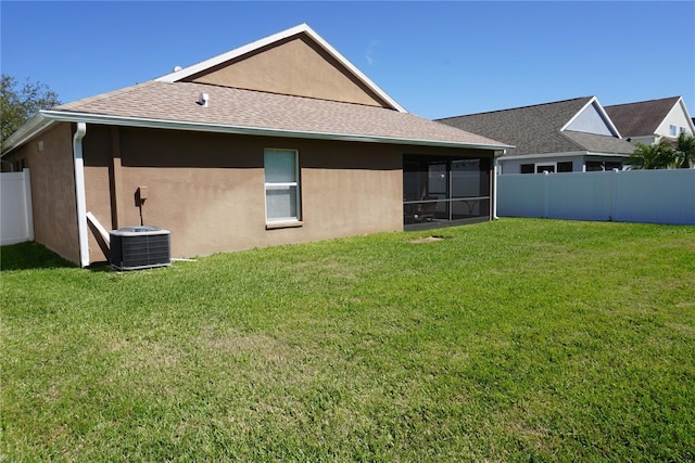 back of house featuring stucco siding, a lawn, fence, a sunroom, and central AC unit