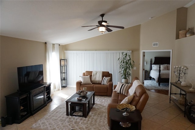 living area featuring light tile patterned floors, visible vents, ceiling fan, and vaulted ceiling