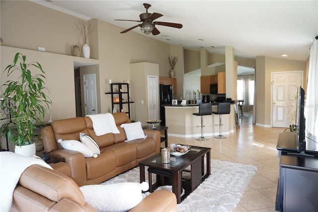 living room featuring light tile patterned flooring, baseboards, ceiling fan, and vaulted ceiling