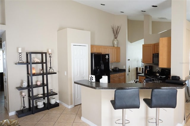 kitchen featuring light tile patterned floors, light brown cabinets, high vaulted ceiling, black fridge with ice dispenser, and dark countertops