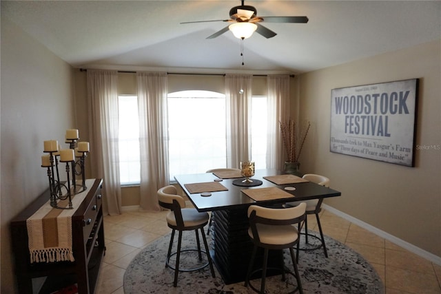 dining space featuring light tile patterned floors, baseboards, and vaulted ceiling