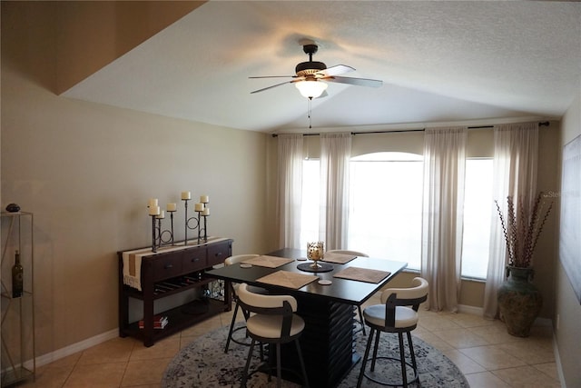 dining area featuring light tile patterned floors, baseboards, ceiling fan, vaulted ceiling, and a textured ceiling