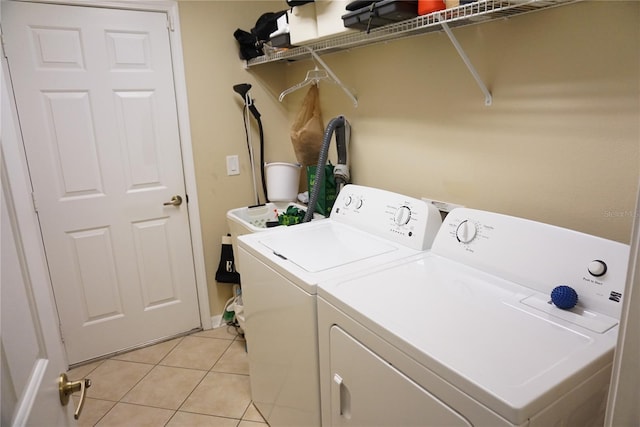 laundry room with washer and clothes dryer, laundry area, and light tile patterned flooring