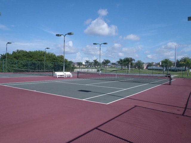 view of tennis court featuring community basketball court and fence