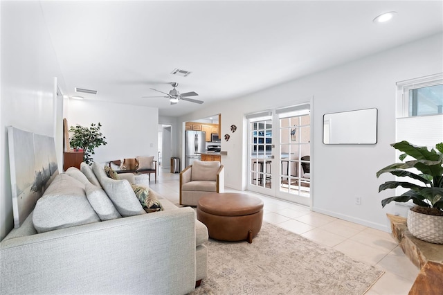 living area featuring light tile patterned floors, visible vents, baseboards, and ceiling fan