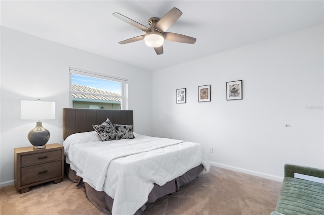 bedroom featuring baseboards, light colored carpet, and ceiling fan