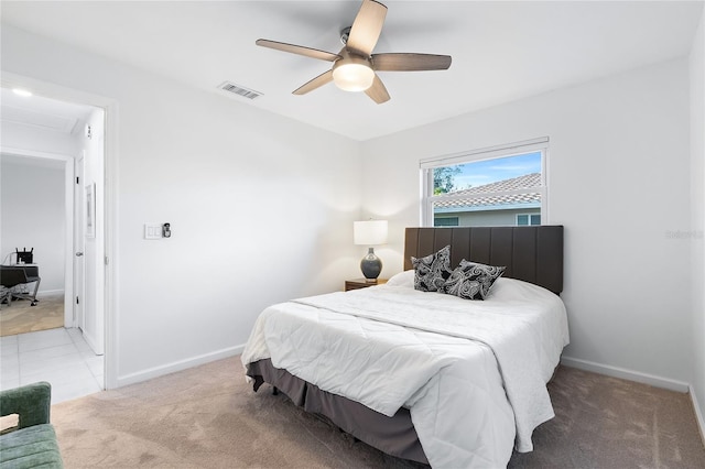 bedroom with visible vents, light colored carpet, baseboards, and ceiling fan