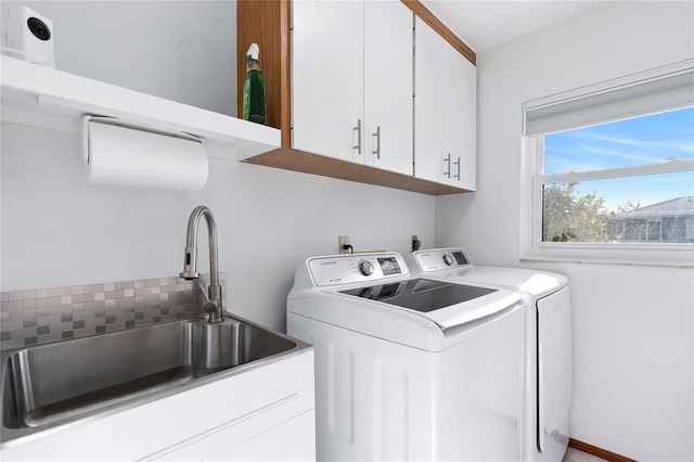 laundry room featuring washer and clothes dryer, cabinet space, and a sink